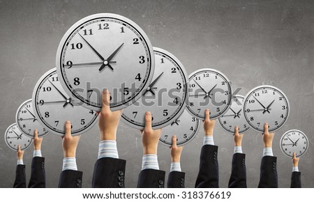 Many hands of business people holding alarm clock
