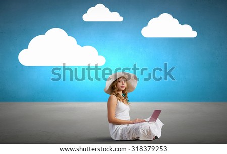 Young lady sitting on floor with laptop on knees