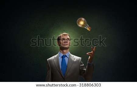 Young businessman pointing with finger at glowing light bulb