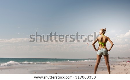 Rear view of young pretty woman in bikini and shorts with shopping bags