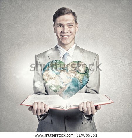 Young businessman with opened book in hands. Elements of this image are furnished by NASA