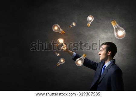 Businessman reaching hand to touch glass light bulb