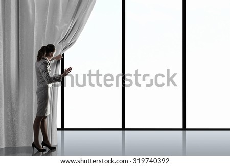 Businesswoman pulling curtain and cityscape behind it