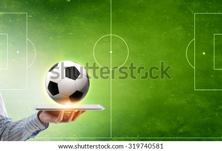 Tablet pc in male hand and soccer ball on screen