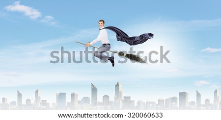 Young businessman flying on broom high in sky