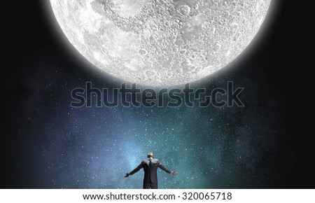Businessman with hands spread apart looking at moon above