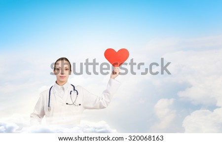Young female doctor holding red heart in hands