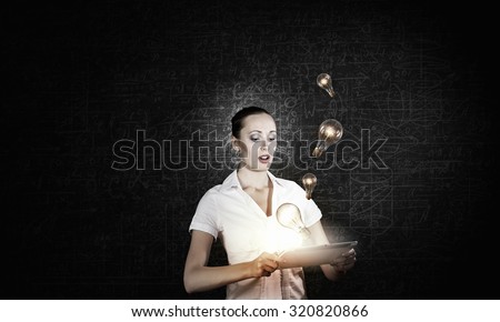Young businesswoman using tablet pc and light bulbs flying out