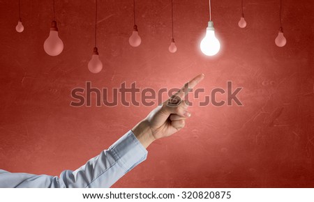 Close up of hand pointing with finger at light bulb