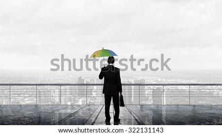 Back view of businessman with umbrella looking at city