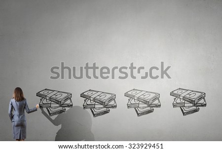 Back view of businesswoman drawing money banknotes on wall