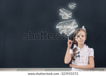Cute school girl pointing at money drawn on blackboard