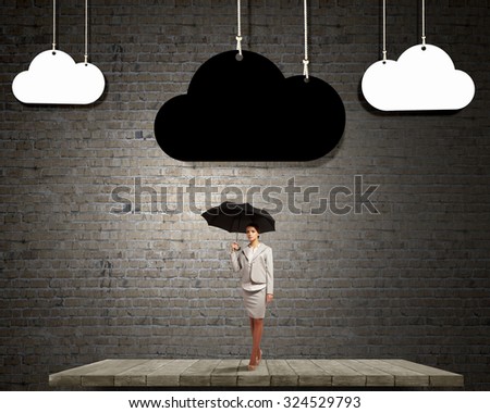 Young businesswoman with black umbrella standing under black cloud