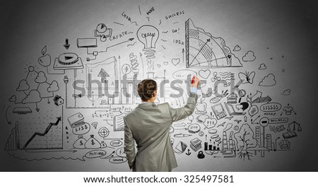 Rear view of businessman drawing business sketch on wall