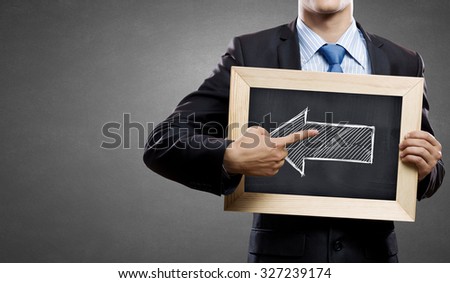 Unrecognizable businessman pointing with finger at arrow on chalkboard