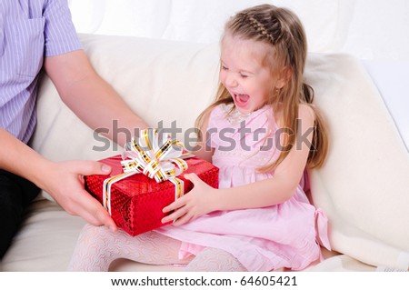 The father gives his young daughter in a red gift box with a white ribbon.