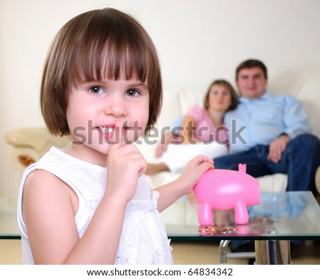 A little girl hides her money in the pig piggy bank.