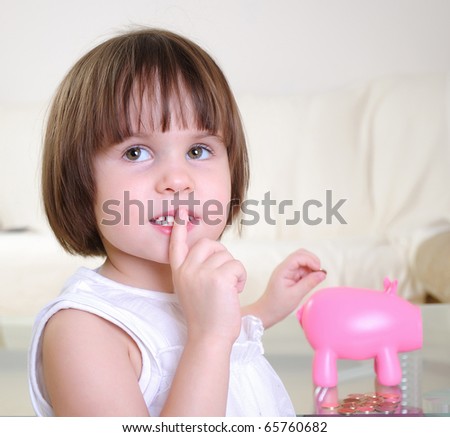 A little girl hides her money in the pig piggy bank.