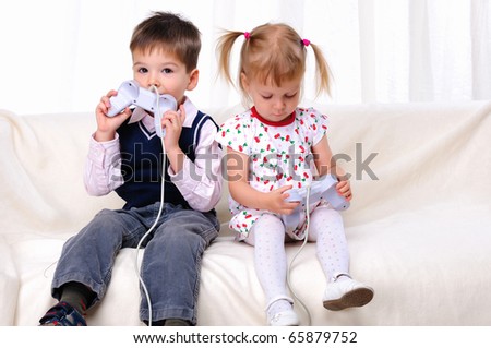 Little brother and sister playing video games lying on the couch
