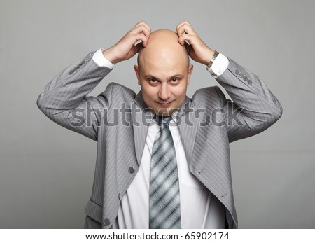 Bald businessman in a gray suit with a gray background. Funny business