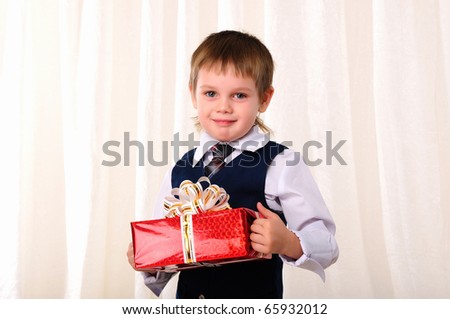 Portrait of a young boy in a blue vest with red gift in hands