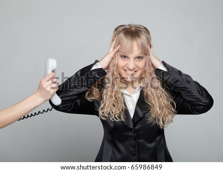 Funny business woman in a black suit with a gray background is angry phone call