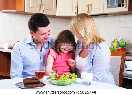 Dad, Mom and their little daughter lunching together in his kitchen.