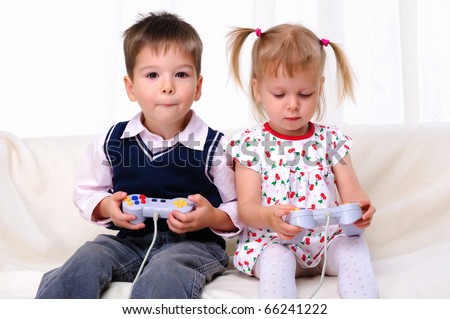 Little brother and sister playing video games lying on the couch