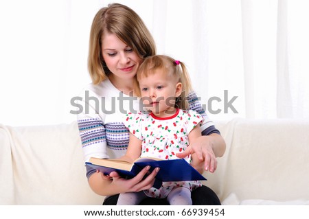 Mother and daughter reading a book together on the couch