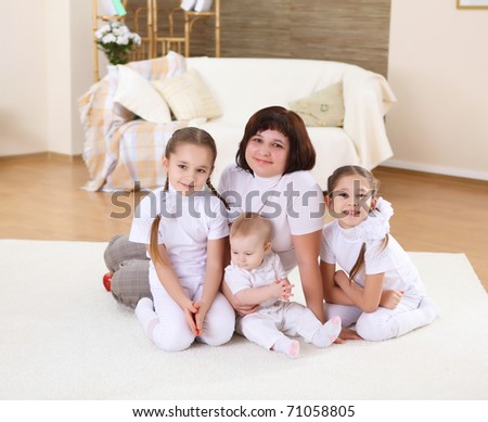 mother with her three daughters at home on the carpet in the living  room