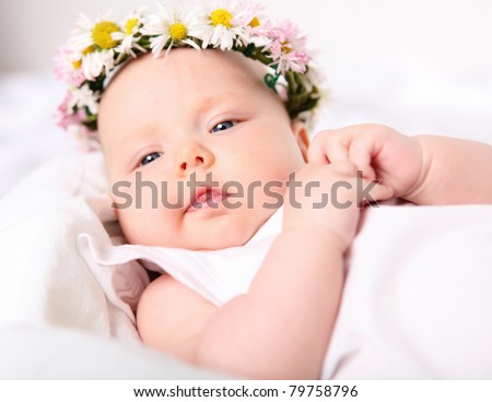 Portrait of a baby with a wreath of flowers on her head.