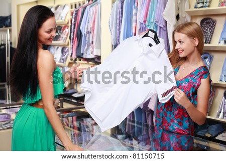 Girl seller helps shoppers choose the clothes in the store