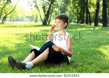 Portrait of a boy sitting with a book in the park