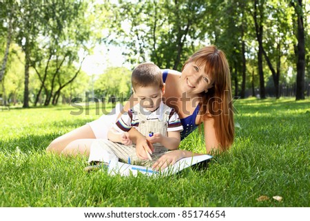 Mother with little son in the park reading a book
