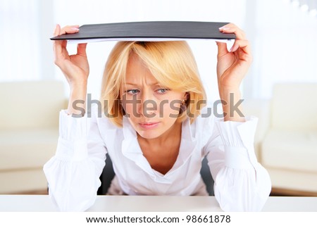 portrait of young stressed business woman hiding under papers