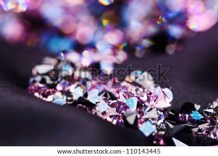 Diamond (small purple jewel) stones heap over black silk cloth background