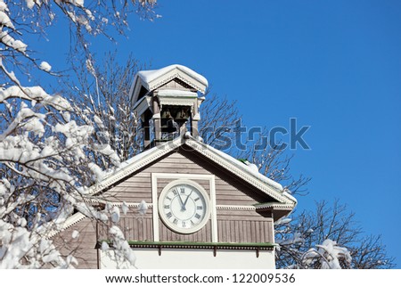 Old wooden snow covered chapel with clock
