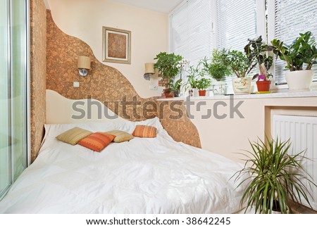 Sunny bedroom on balcony interior with Window and plants, wide angle view