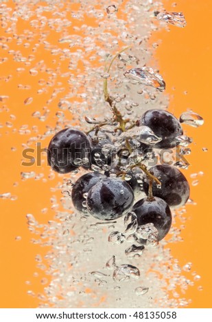Bunch of grapes floating in yellow water with air bubbles