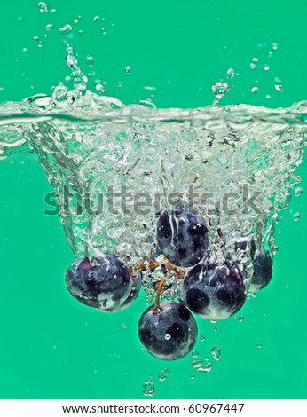 Bunch of grapes floating in green water with air bubbles