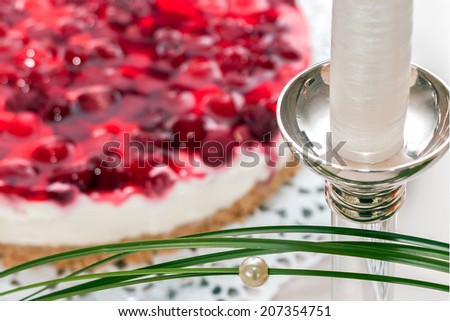 Part of a silver-chandelier in front of a berry-cake