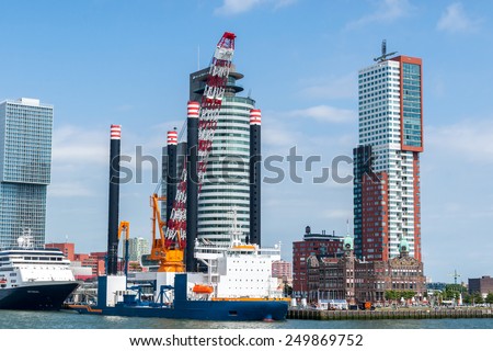Rotterdam, Netherlands - June 21st, 2014: Rotterdam\'s modern architecture at Wilhelminapier overlooking a construction vessel for the construction of offshore wind farms and the MS Rotterdam VI