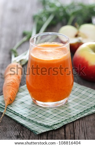 Fresh juice from apples and carrots on wooden background