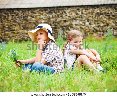 Little boy wants to give flowers to the little girl near the country house