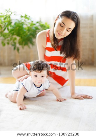 Happy smiling mother with eight month old baby girl indoor