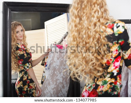 Woman shopping dresses looking in mirror in clothing store