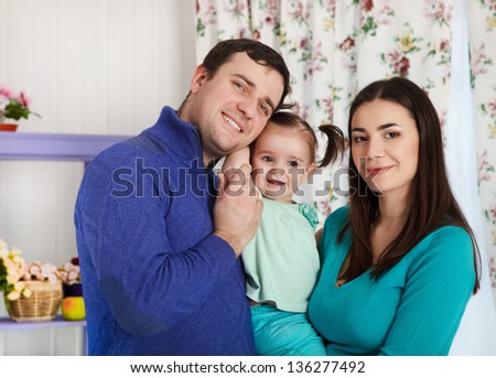 Happy smiling family with one year old baby girl indoor
