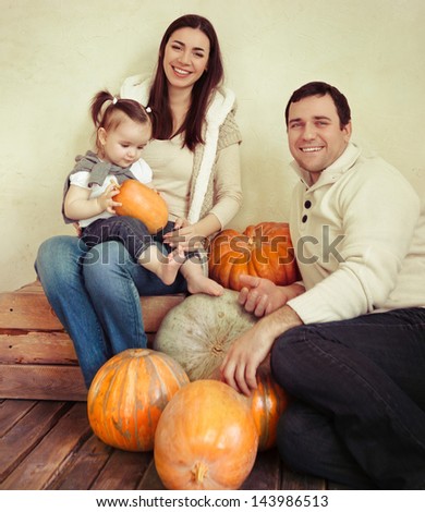 Happy smiling family with autumn pumpkin indoor