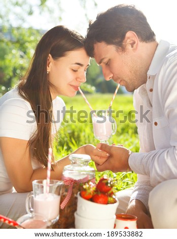 Young happy couple in love drinking milk shake at spring picnic in spring day. Outdoors portrait