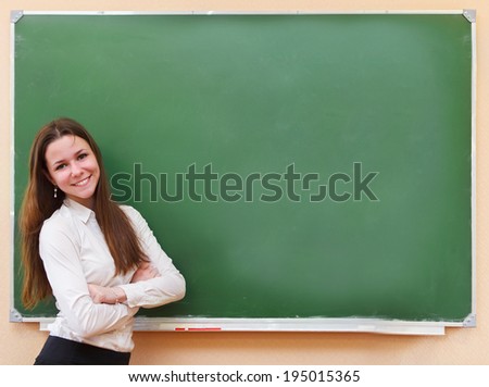 Student girl standing near clean blackboard in the classroom